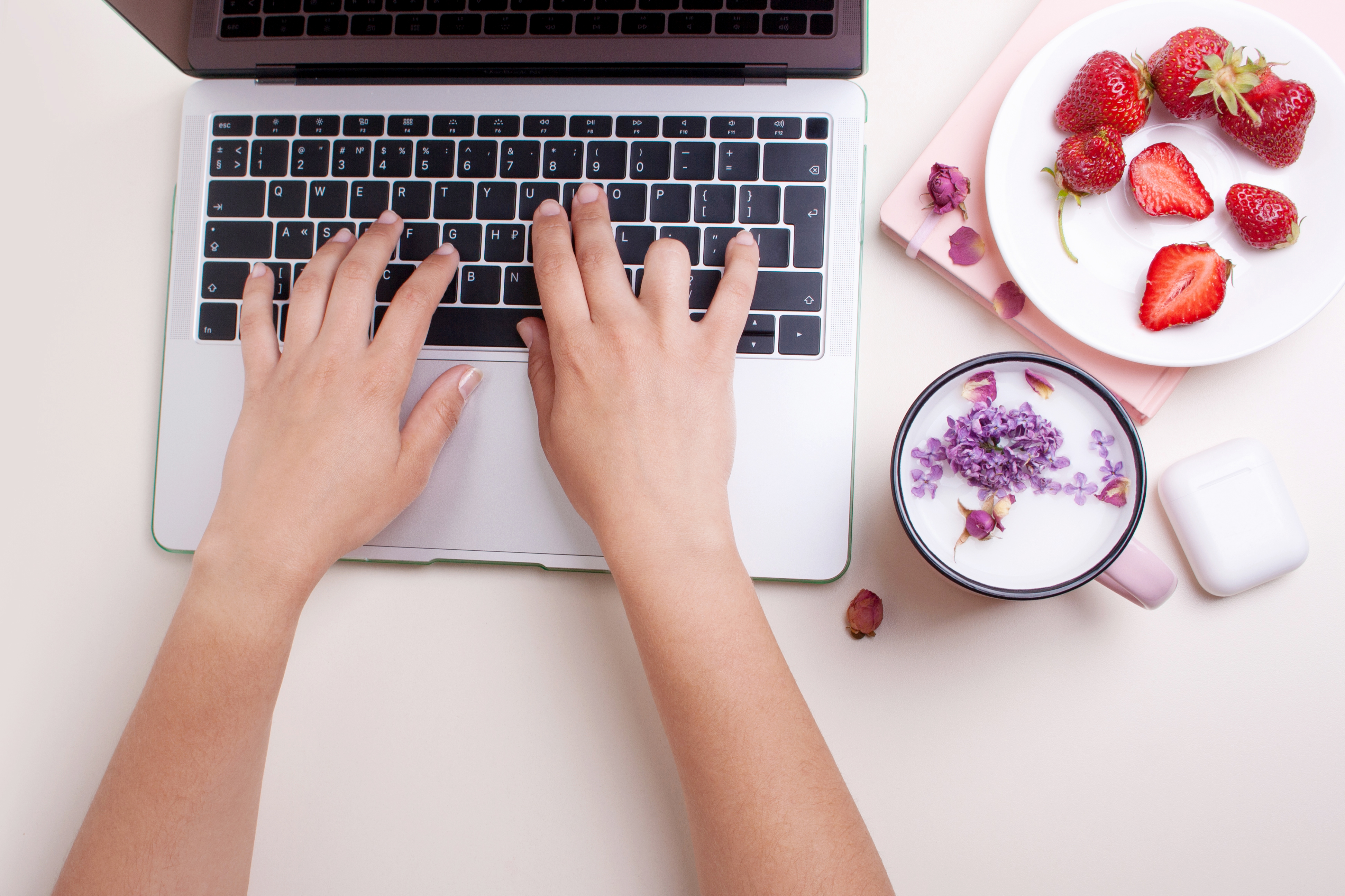 Hands are typing on a laptop keyboard. Workplace. Cup of cocktai